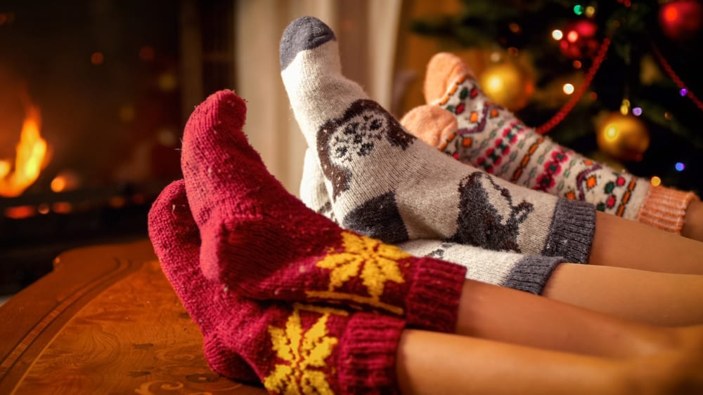 three people wearing knit holiday socks